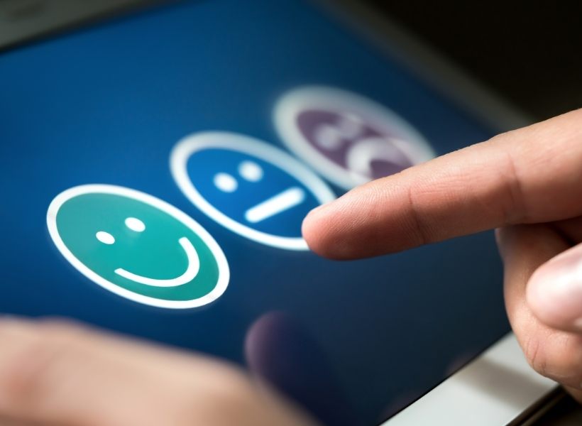 User Experience Concept with Three Faces - Sad, Neutral, and Happy - Person pointing on tablet